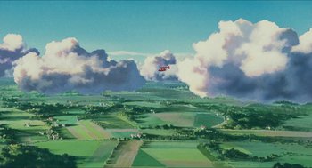 Movie still from “Porco Rosso” (1992), directed by Hayao Miyazaki – An airplane flying over a green field under a cloudy sky; Extreme Wide shot, Low angle