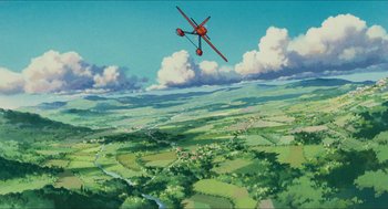 Movie still from “Porco Rosso” (1992), directed by Hayao Miyazaki – An airplane flying over a lush green field; Extreme Wide shot, Low angle