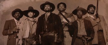 Movie still from “Posse” (1993), directed by Mario Van Peebles – A black and white photo of a group of men with guns; Medium shot, Low angle