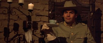 Movie still from “Posse” (1993), directed by Mario Van Peebles – A man in a uniform holding a cup of tea; Medium shot, Low angle