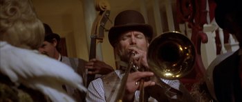 Movie still from “Posse” (1993), directed by Mario Van Peebles – A man in a top hat playing a trombone; Close Up shot, Low angle