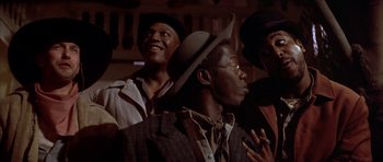 Movie still from “Posse” (1993), directed by Mario Van Peebles – A group of men standing next to each other in a room; Close Up shot, Low angle