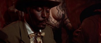 Movie still from “Posse” (1993), directed by Mario Van Peebles – A man with a cigar in his mouth and wearing a hat; Close Up shot, Low angle