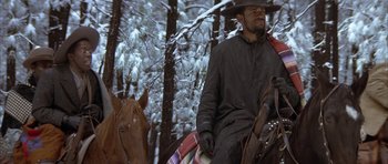 Movie still from “Posse” (1993), directed by Mario Van Peebles – A man riding a horse through the snow covered woods; Medium shot, Low angle