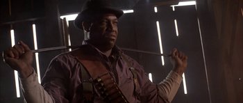 Movie still from “Posse” (1993), directed by Mario Van Peebles – A man in a hat holding a stick in his hand; Close Up shot, Low angle
