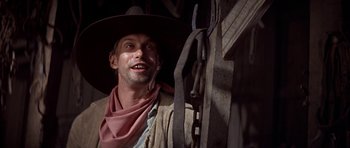 Movie still from “Posse” (1993), directed by Mario Van Peebles – A man in a cowboy hat standing in front of a wooden structure; Close Up shot, Low angle
