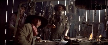 Movie still from “Posse” (1993), directed by Mario Van Peebles – A group of men standing next to each other in a room; Medium shot, Low angle