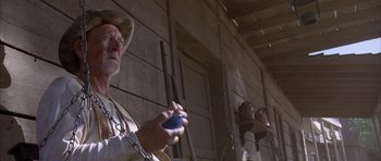 Movie still from “Posse” (1993), directed by Mario Van Peebles – An older man holding a cell phone while standing in front of a building; Close Up shot, Low angle