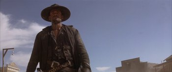 Movie still from “Posse” (1993), directed by Mario Van Peebles – A man wearing a cowboy hat and a leather jacket; Medium shot, Low angle