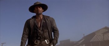 Movie still from “Posse” (1993), directed by Mario Van Peebles – A man wearing a hat and a leather jacket; Medium shot, Low angle