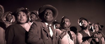 Movie still from “Posse” (1993), directed by Mario Van Peebles – A black and white photo of a group of men in hats; Medium shot, Low angle