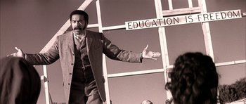 Movie still from “Posse” (1993), directed by Mario Van Peebles – A black and white photo of a man in a suit; Medium shot, Low angle