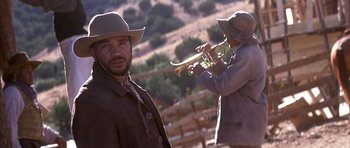 Movie still from “Posse” (1993), directed by Mario Van Peebles – A man in a cowboy hat is playing a trumpet; Close Up shot, Low angle