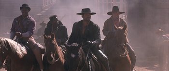 Movie still from “Posse” (1993), directed by Mario Van Peebles – A group of men riding on the backs of horses; Medium shot, Low angle