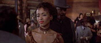 Movie still from “Posse” (1993), directed by Mario Van Peebles – A woman in a dress and a man in a hat; Close Up shot, Over the shoulder angle