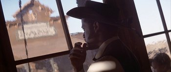 Movie still from “Posse” (1993), directed by Mario Van Peebles – A man in a cowboy hat looking out of a window; Close Up shot, Low angle