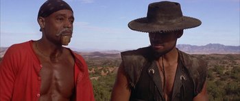 Movie still from “Posse” (1993), directed by Mario Van Peebles – Two men standing next to each other on top of a hill; Close Up shot, Low angle