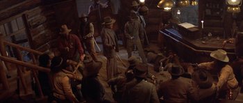 Movie still from “Posse” (1993), directed by Mario Van Peebles – A group of men in suits and hats on a stage; Wide shot, High angle