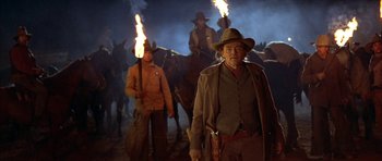 Movie still from “Posse” (1993), directed by Mario Van Peebles – A man with a gun standing in front of a group of horses; Medium shot, Low angle