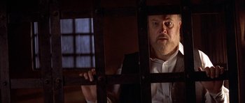 Movie still from “Posse” (1993), directed by Mario Van Peebles – A man in a jail cell looking through bars; Close Up shot, Over the shoulder angle