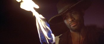 Movie still from “Posse” (1993), directed by Mario Van Peebles – A man in a cowboy hat holding a bottle of beer; Close Up shot, Low angle