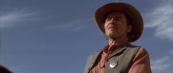 Movie still from “Posse” (1993), directed by Mario Van Peebles – An older man wearing a hat and a brown jacket; Close Up shot, Low angle