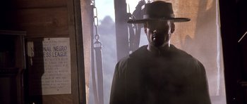 Movie still from “Posse” (1993), directed by Mario Van Peebles – A man wearing a hat standing in front of a window; Close Up shot, Low angle