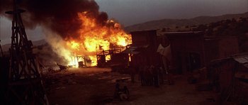 Movie still from “Posse” (1993), directed by Mario Van Peebles – A group of people standing in front of a burning building; Extreme Wide shot, High angle