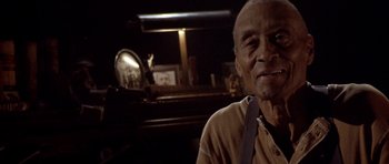 Movie still from “Posse” (1993), directed by Mario Van Peebles – An older man is smiling for the camera; Close Up shot, Low angle