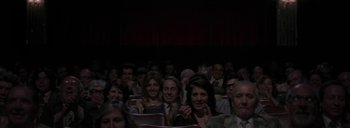 Movie still from “Post Mortem” (2010), directed by Pablo Larraín – A group of people sitting in a theater clapping; Wide shot, Over the shoulder angle