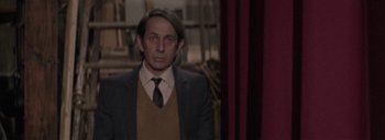 Movie still from “Post Mortem” (2010), directed by Pablo Larraín – A man in a suit and tie standing in front of a window; Medium shot, Low angle