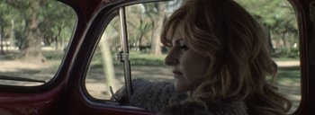 Movie still from “Post Mortem” (2010), directed by Pablo Larraín – A woman with red hair sitting in the driver's seat of a car; Close Up shot, Low angle