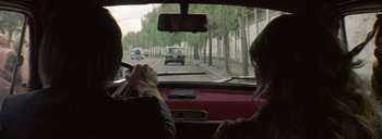 Movie still from “Post Mortem” (2010), directed by Pablo Larraín – A man and a woman driving a car down a street; Medium shot, Over the shoulder angle