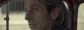 Movie still from “Post Mortem” (2010), directed by Pablo Larraín – A man's face with a green eye; Close Up shot, Low angle