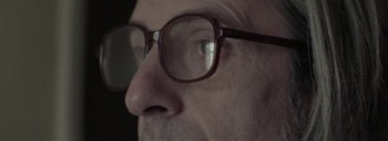 Movie still from “Post Mortem” (2010), directed by Pablo Larraín – A man's face wearing glasses; Extreme Close Up shot, Low angle