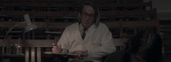 Movie still from “Post Mortem” (2010), directed by Pablo Larraín – A man in a white lab coat writing on a piece of paper; Medium shot, Low angle