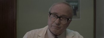 Movie still from “Post Mortem” (2010), directed by Pablo Larraín – An older man wearing glasses and a white jacket; Close Up shot, Low angle