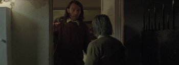 Movie still from “Post Mortem” (2010), directed by Pablo Larraín – A man in a brown shirt is talking to another man; Medium shot, Over the shoulder angle
