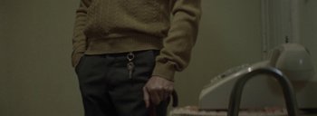 Movie still from “Post Mortem” (2010), directed by Pablo Larraín – A man in a brown sweater holding a pair of keys; Extreme Close Up shot, High angle