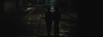 Movie still from “Post Mortem” (2010), directed by Pablo Larraín – A couple of people that are standing next to each other; Wide shot, Over the shoulder angle