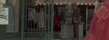 Movie still from “Post Mortem” (2010), directed by Pablo Larraín – A group of people standing in front of a metal gate; Wide shot, Low angle