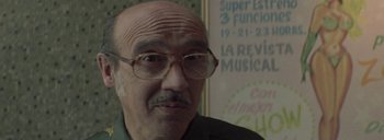 Movie still from “Post Mortem” (2010), directed by Pablo Larraín – An older man wearing glasses and a green shirt; Close Up shot, Low angle