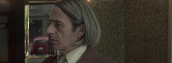 Movie still from “Post Mortem” (2010), directed by Pablo Larraín – A person wearing a suit and tie; Close Up shot, Over the shoulder angle