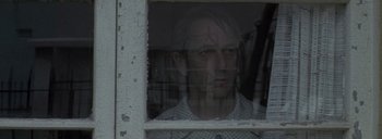 Movie still from “Post Mortem” (2010), directed by Pablo Larraín – A man looking out of a broken window; Close Up shot, Low angle