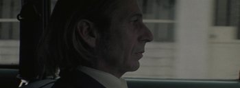 Movie still from “Post Mortem” (2010), directed by Pablo Larraín – A person wearing a suit and tie; Close Up shot, Over the shoulder angle