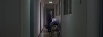 Movie still from “Post Mortem” (2010), directed by Pablo Larraín – A man standing next to an empty hospital bed; Wide shot, High angle