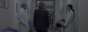 Movie still from “Post Mortem” (2010), directed by Pablo Larraín – A man and a woman are standing in front of a door; Medium shot, Over the shoulder angle