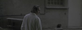 Movie still from “Post Mortem” (2010), directed by Pablo Larraín – A man standing in front of a window; Medium shot, Over the shoulder angle