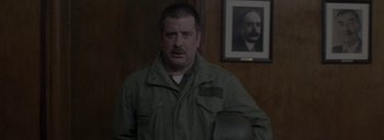 Movie still from “Post Mortem” (2010), directed by Pablo Larraín – A man standing in front of a wall with a picture on the wall; Medium shot, Over the shoulder angle