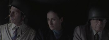 Movie still from “Post Mortem” (2010), directed by Pablo Larraín – A woman is looking at the camera while sitting in a dark room; Close Up shot, High angle